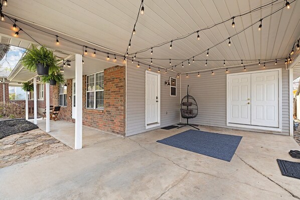 A covered patio with string lights, a hanging chair, and a door. - Boho BnB ~ Walk to Cherry/Pickwick & MSU (Springfield)
