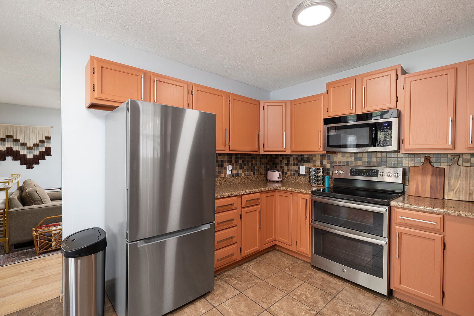 A modern kitchen with stainless steel appliances, wooden cabinets, and a tiled backsplash.
