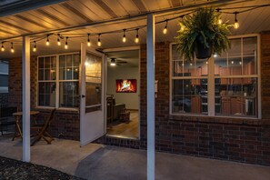 A covered patio area with string lights, a hanging plant, and a view into the house. - Boho BnB ~ Walk to Cherry/Pickwick & MSU (Springfield)