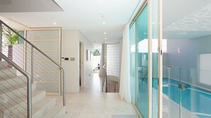 A modern hotel interior with a glass-enclosed pool, a staircase with metal railings, and a clean, minimalist design. - Gordons Bay Vista (Clovelly)