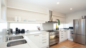 A modern kitchen with white cabinetry, stainless steel appliances, a gas stove, and a built-in oven. - Gordons Bay Vista (Clovelly)