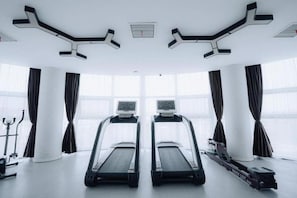Un gimnasio con dos cintas de correr, una máquina de remo y una bicicleta estática.