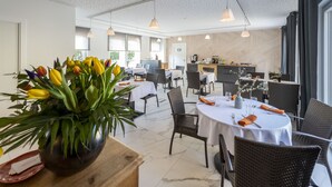 Un comedor moderno con mesas redondas, sillas de mimbre y un arreglo floral central.