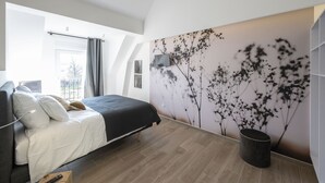 Un dormitorio moderno con una cama grande, un televisor montado en la pared y vistas al exterior.