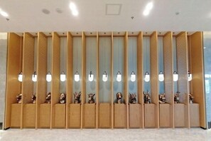 A reception area with a wooden reception desk, multiple light fixtures, and decorative animal sculptures. - Mingcheng Xincheng Hotel (Sanming)