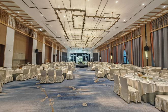 A banquet hall with round tables, chairs, and a carpeted floor.