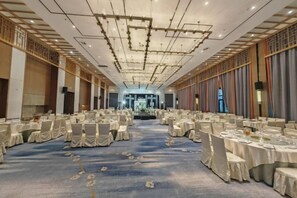 Un salón de banquetes con mesas redondas, sillas y piso alfombrado.