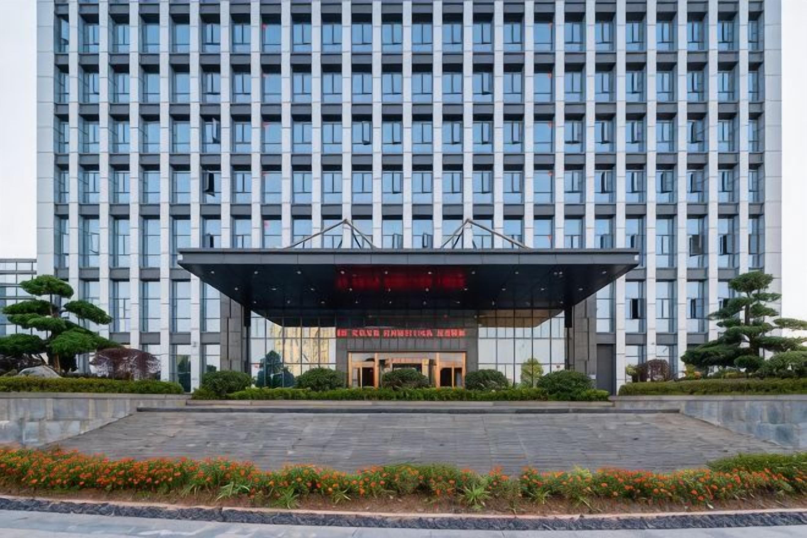 Un bâtiment moderne doté d’une grande entrée et d’un écran numérique placé au-dessus des portes.