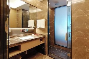 Un baño moderno con tocador de mármol, un espejo grande y cabina de ducha de vidrio.