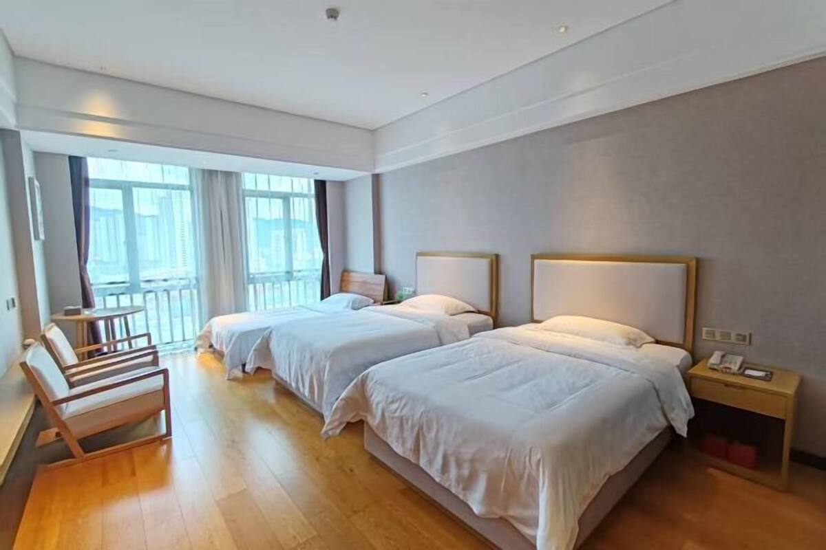 A hotel room with two beds, a balcony, a desk, and a nightstand.