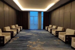 A conference room with a carpeted floor, rows of chairs, and a large window with curtains. - Mingcheng Xincheng Hotel (Sanming)
