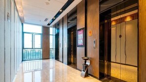 Un pasillo moderno de hotel con piso pulido, una recepción y un ascensor.