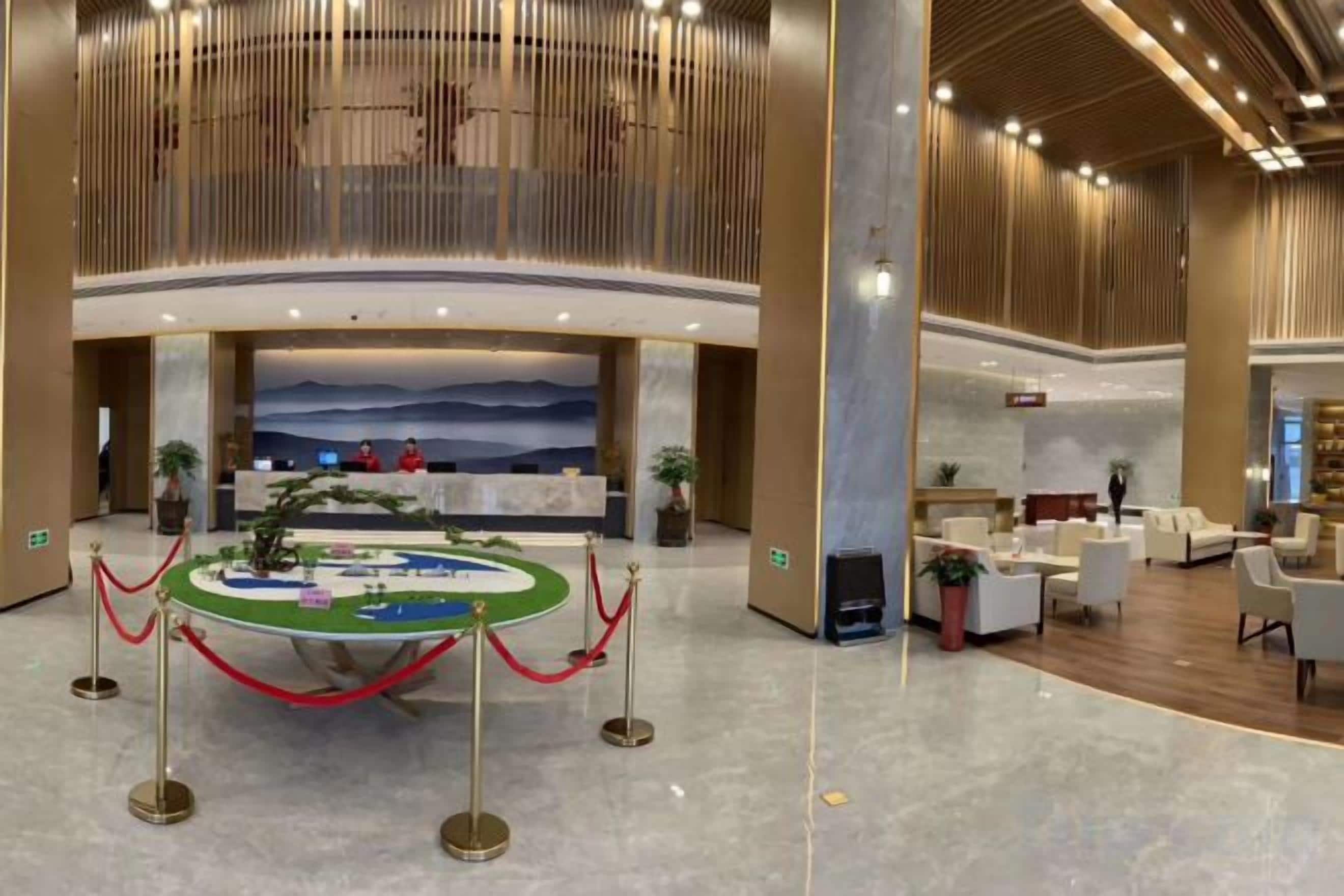 Eine großzügige Lobby mit einer Rezeption, einer Sitzecke und einem großen Wandgemälde.