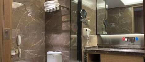 Un baño moderno con pared de mármol, inodoro, lavabo con espejo y perchero para toallas.