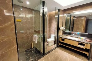 A modern bathroom with a glass shower enclosure, a toilet, a sink with a mirror, and marble flooring.
