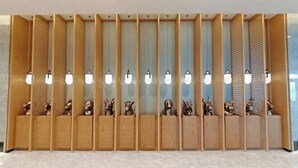 Una zona de recepción con varios paneles de madera y una fila de luces fijadas a la pared.