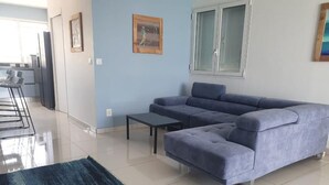 A living room with a blue sofa, a small table, and a dark blue rug. - Appartement Duplex Bord de mer à Proximité de Tout ! (Saint-François)