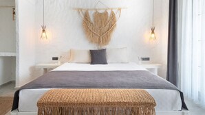 A modern bedroom with a large bed, two bedside tables, a wall-mounted macrame piece, and a woven bench.