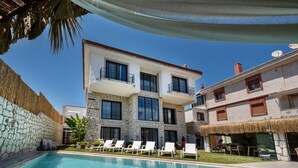 A two-story building with a swimming pool, white walls, and balconies.