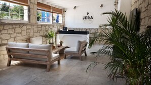 A cozy indoor seating area with a stone wall, wooden furniture, and a reception desk.