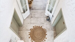A narrow hallway with two white doors, a woven rug in the center, and a small plant on the floor.