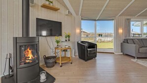 A modern living room with a fireplace, a television, and a view of the outdoors. - Cozy home in Haderslev with sauna (Haderslev)