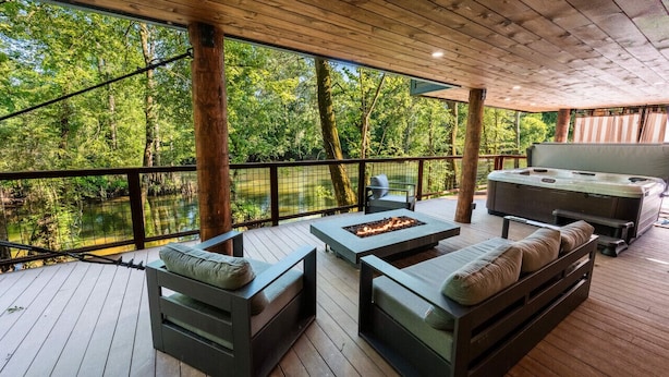 Une terrasse extérieure couverte, dotée d’un plancher en bois, de sièges intégrés, d’un foyer et d’un barbecue.