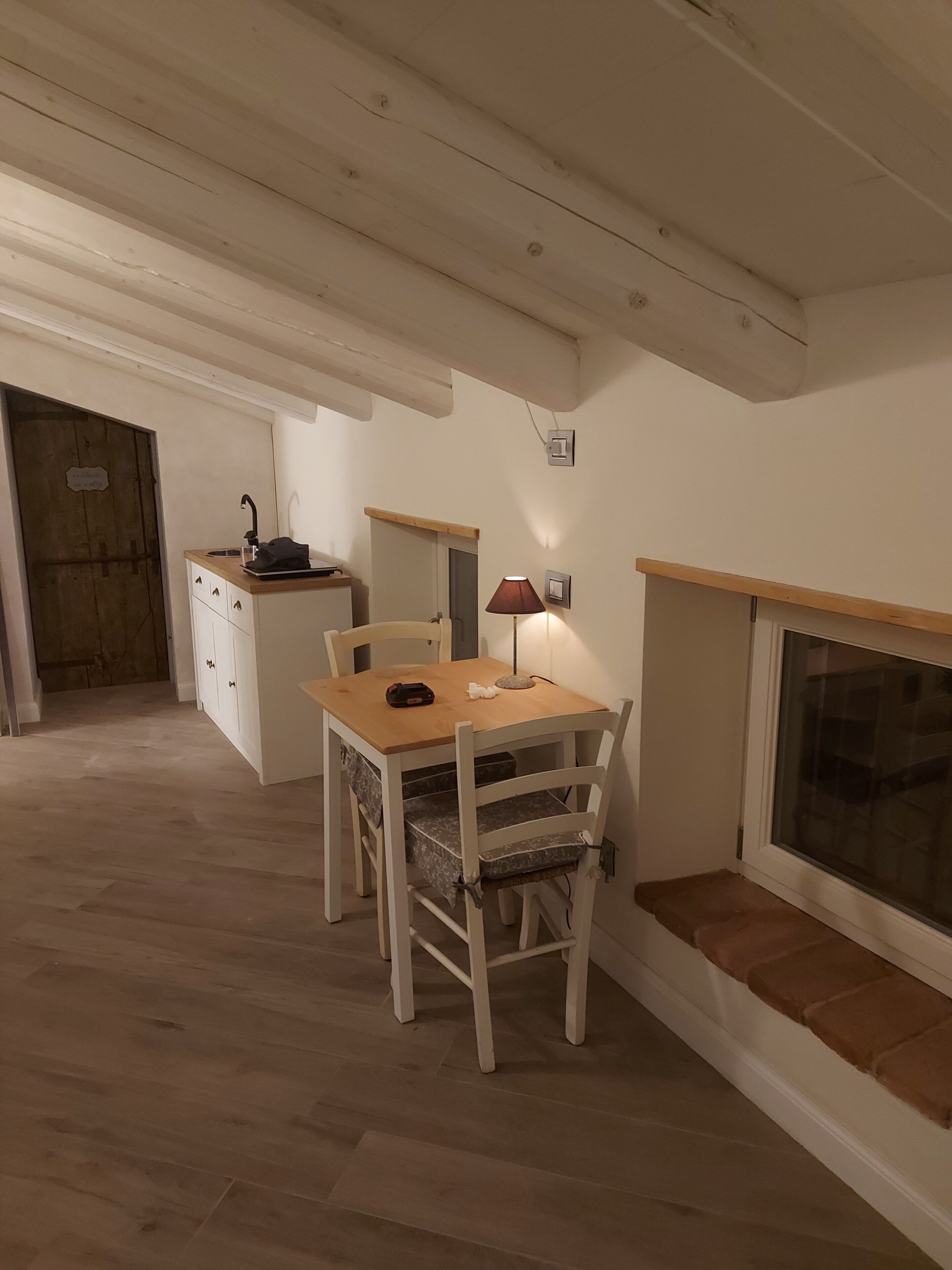 A cozy room with a wooden dining table, a bench, a small kitchen area, and a fireplace.