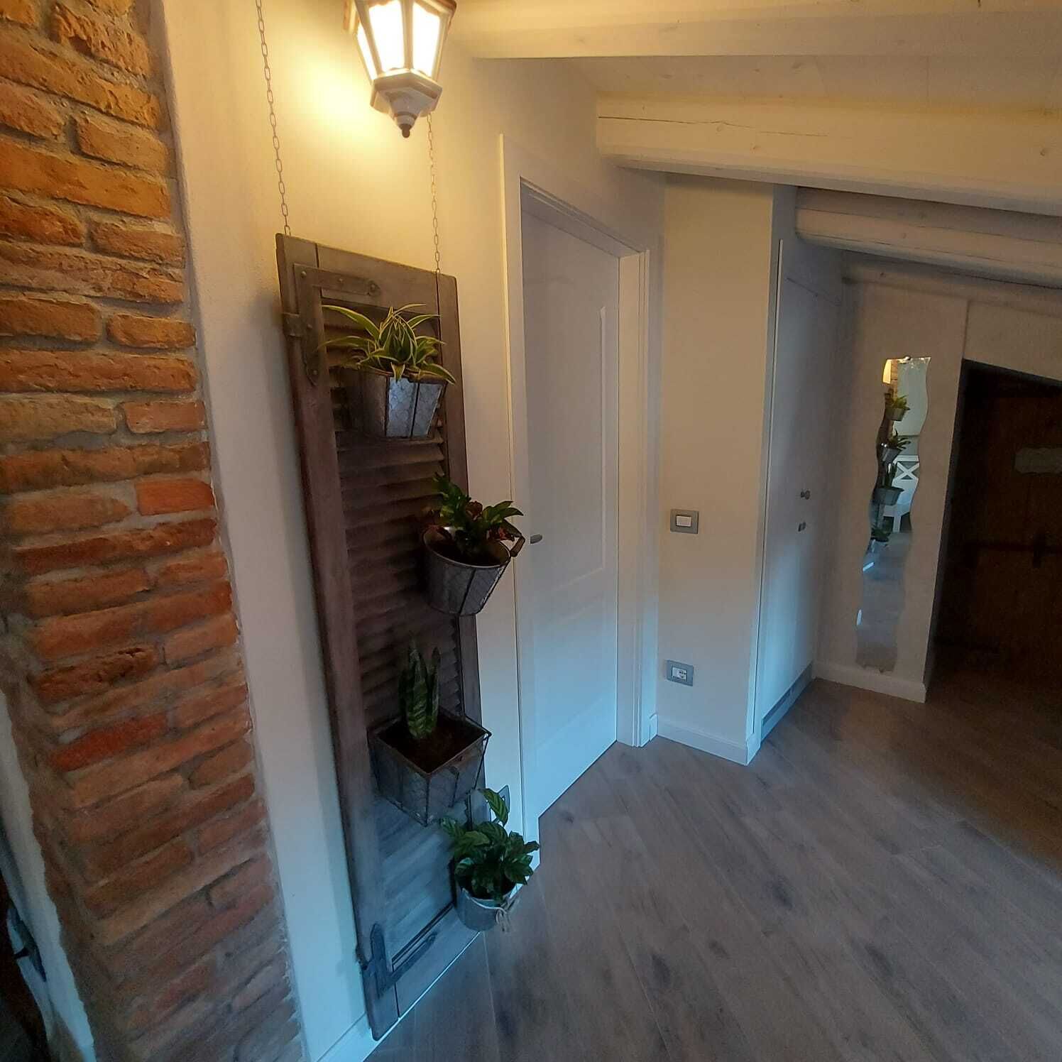 A hallway with a brick wall, wooden slats, and hanging plants.