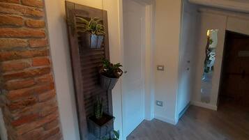 A hallway with a brick wall, wooden slats, and hanging plants.