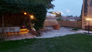 Un patio con suelo de piedra, mobiliario de madera y una maceta grande.