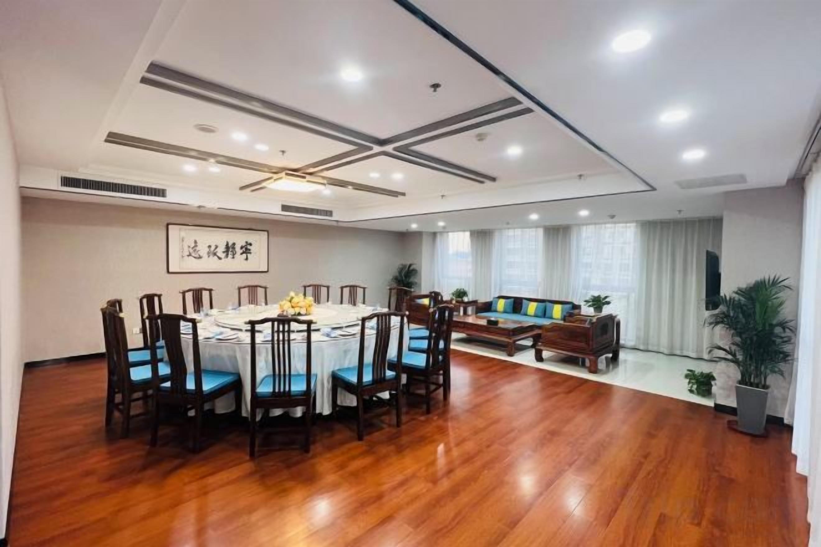 A spacious room with a round dining table surrounded by chairs, a sofa, and a television.