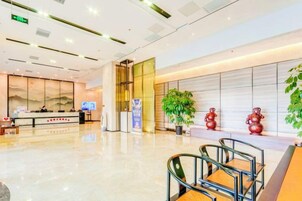Un vestíbulo moderno con mostrador de recepción, zona de estar y elementos decorativos.