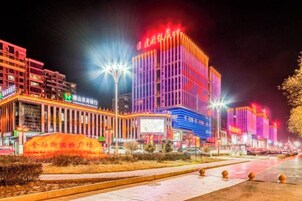 Una calle urbana iluminada con edificios modernos, faroles y un cielo despejado.