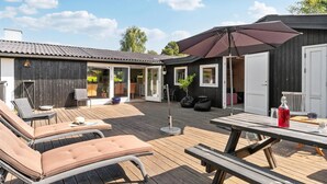 A wooden deck with lounge chairs and a picnic table, a covered patio area, and a small building with sliding glass doors. - Awesome home in Gilleleje with WiFi (Gilleleje)