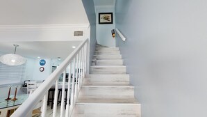 A staircase with white railings leading to a dining area with a glass table and chairs. - Awesome Oceanfront Grd Flr Condo on Spectacular 7 Mile Beach – #19 TIC (Grand Cayman)