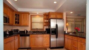 Une cuisine moderne avec des meubles en bois, un réfrigérateur en acier inoxydable et un four à micro-ondes.