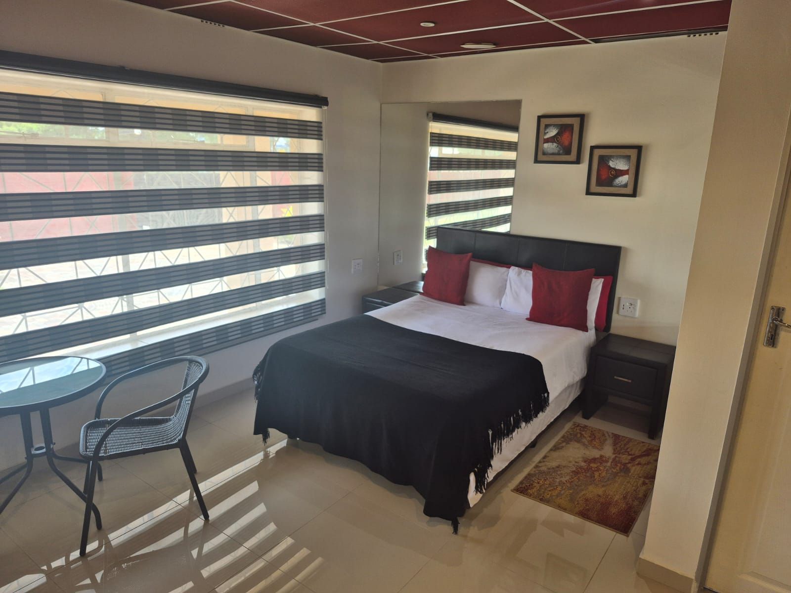 A bedroom with a bed, a nightstand, a chair, and a window with blinds.