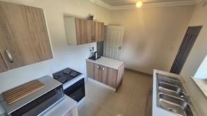 A compact kitchen with a stove, oven, microwave, and a sink.