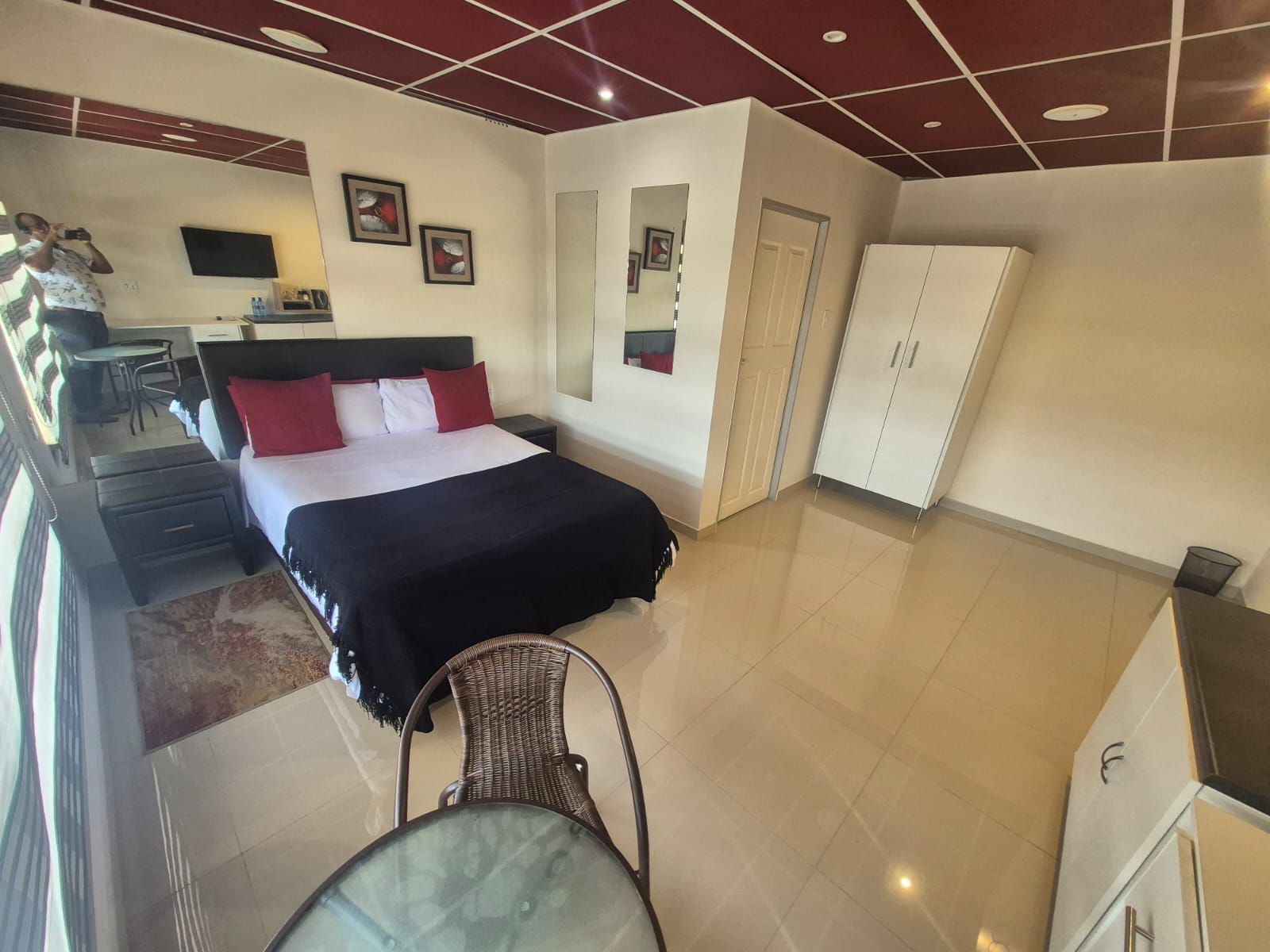 A hotel room with a bed, a desk, a chair, a wardrobe, and a TV.