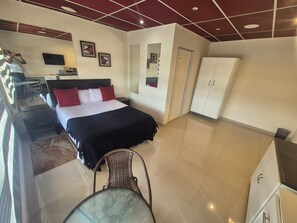 Een hotelkamer met een bed, bureau, stoel, kledingkast en televisie.