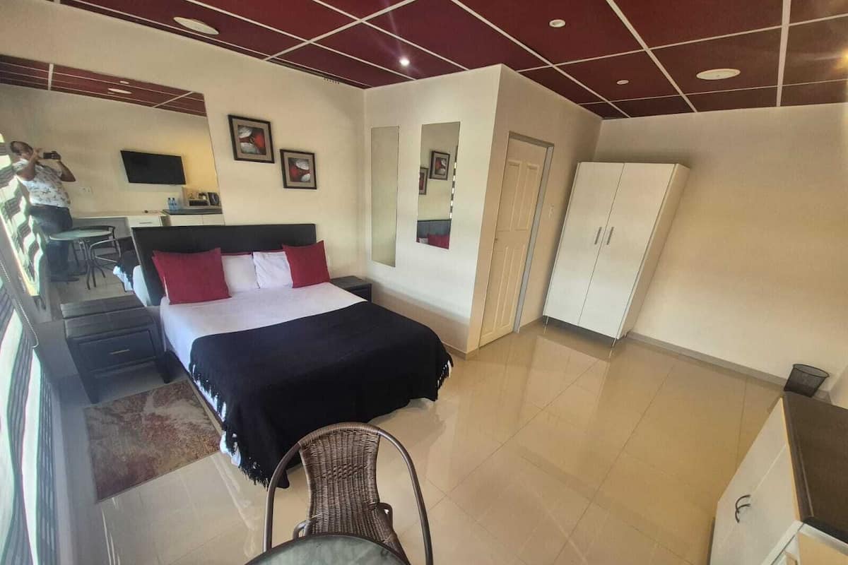 Une chambre d’hôtel équipée d’un lit, d’un bureau, d’une chaise, d’une armoire et d’un téléviseur.