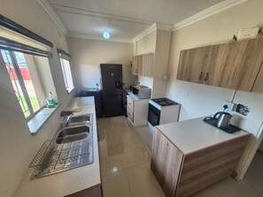 Eine kleine Küche mit Kühlschrank, Mikrowelle, Herd und Spüle.