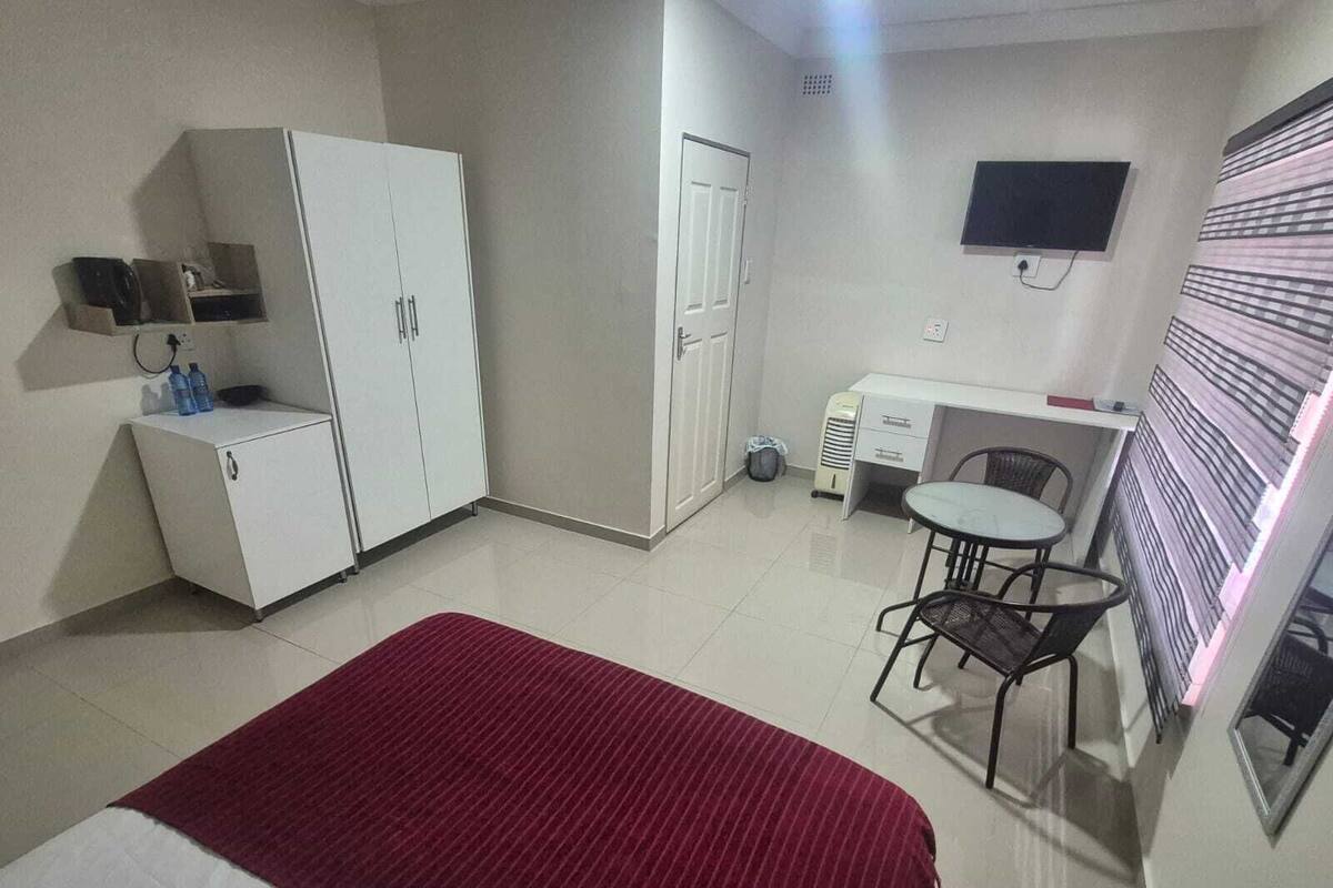 Une chambre d’hôtel de taille réduite, comprenant un lit, un bureau, une chaise, une télévision et une armoire.