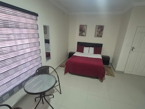 Une chambre à coucher avec un lit, une chaise, une petite table et deux tableaux accrochés au mur.