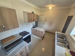 Een kleine keuken met een fornuis, oven, magnetron en een spoelbak.