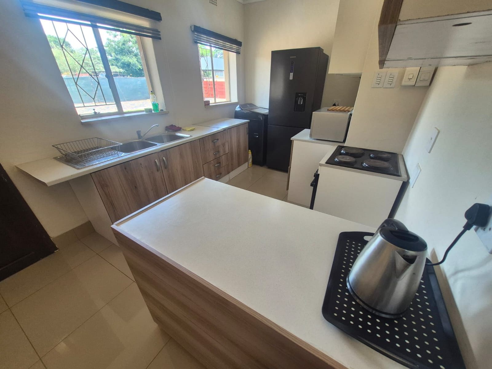 A kitchen with a white countertop, a sink, a black refrigerator, and a stove.