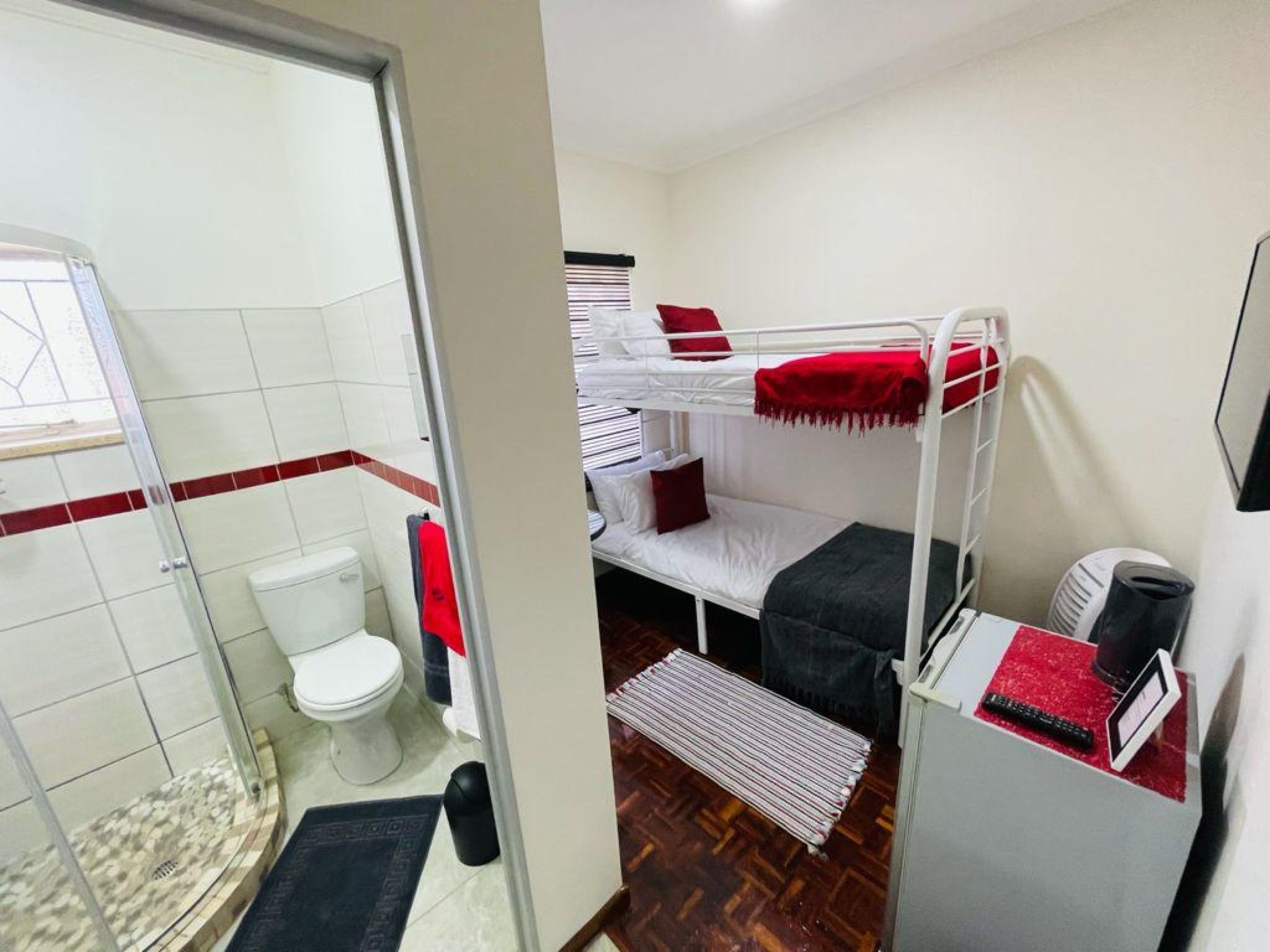 A compact room with a bunk bed, a toilet, and a shower area.