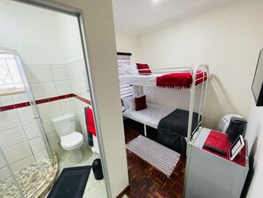 Een kleine kamer met een stapelbed, toilet en douche.