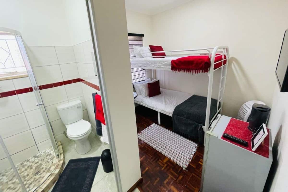 Une petite pièce comprenant un lit superposé, des toilettes et un espace douche.